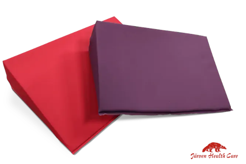 Ein rotes und ein violettes Keilkissen. Dieses wird als Positionierungshilfe in der Pflege eingesetzt.